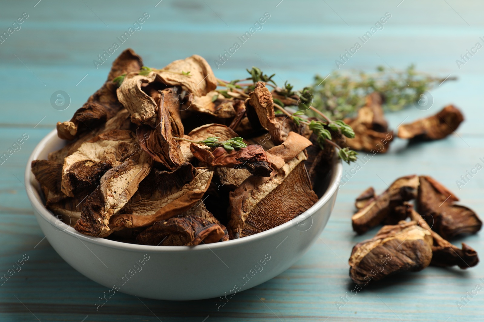 Photo of Dried chanterelle mushrooms with thyme on blue wooden table, closeup