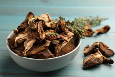 Photo of Dried chanterelle mushrooms with thyme on blue wooden table, closeup
