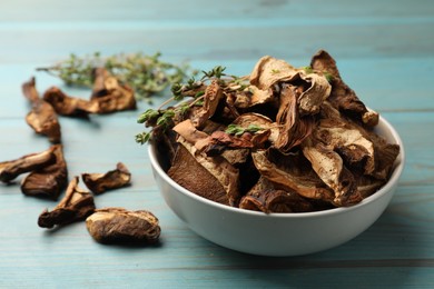 Photo of Dried chanterelle mushrooms with thyme on blue wooden table, closeup