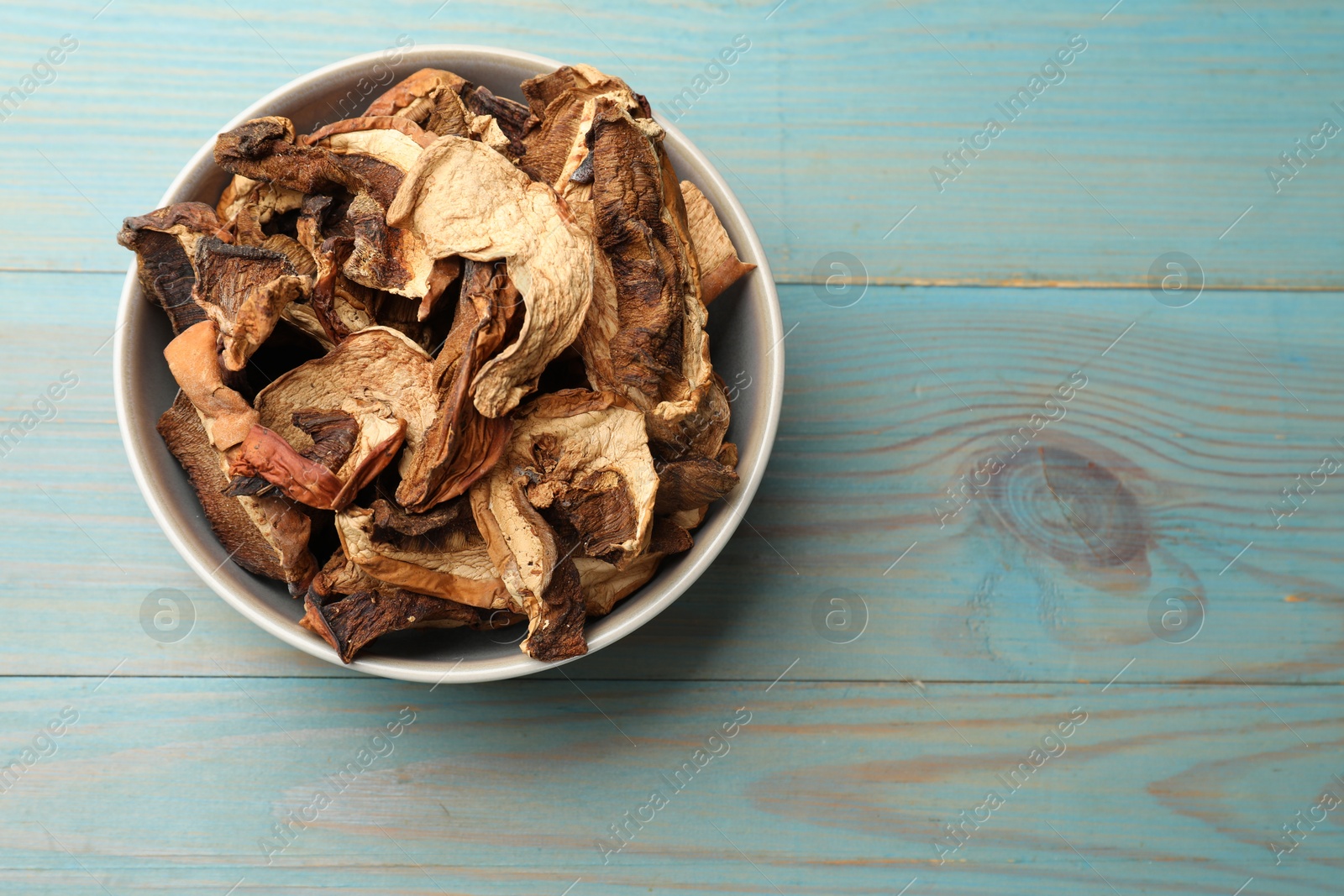 Photo of Dried chanterelle mushrooms on blue wooden table, top view. Space for text