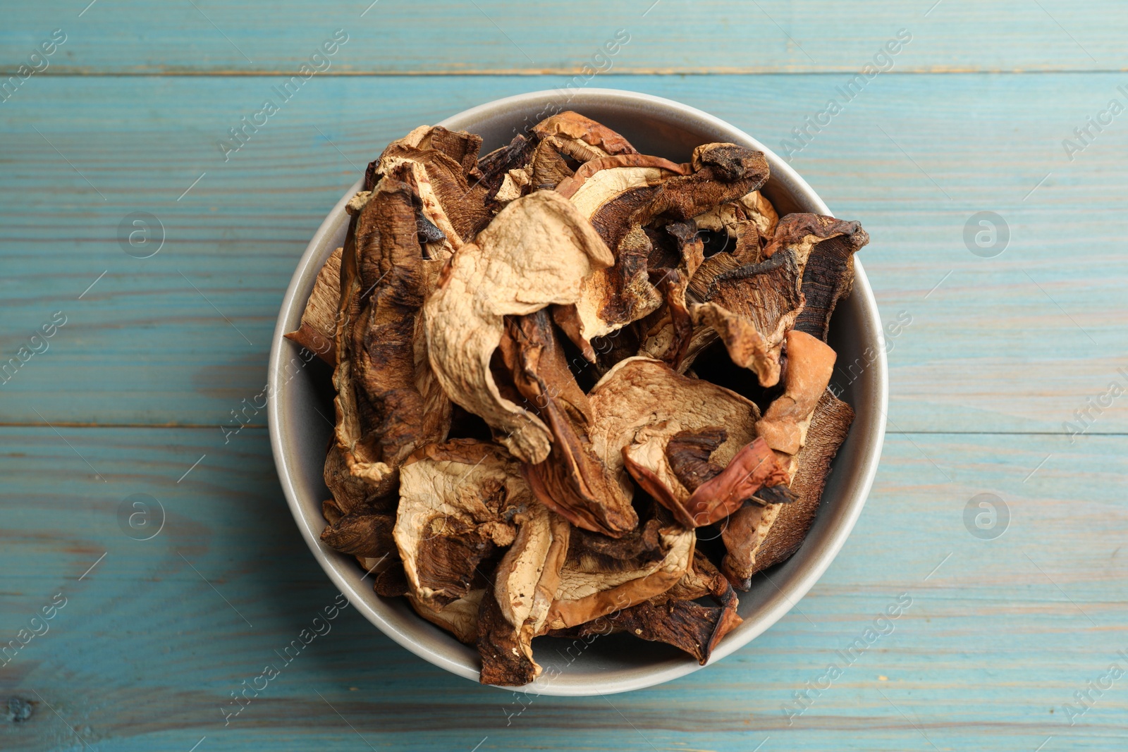 Photo of Dried chanterelle mushrooms on blue wooden table, top view