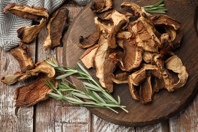 Photo of Dried chanterelle mushrooms with rosemary on wooden table, flat lay