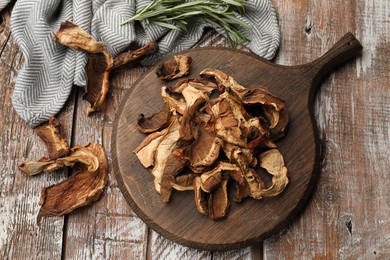 Photo of Dried chanterelle mushrooms with rosemary on wooden table, flat lay