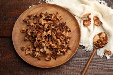 Photo of Dried chanterelle mushrooms and spoon on wooden table, flat lay