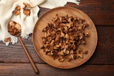 Photo of Dried chanterelle mushrooms and spoon on wooden table, flat lay