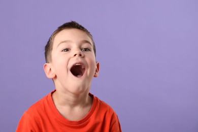 Photo of Portrait of surprised boy on purple background, space for text