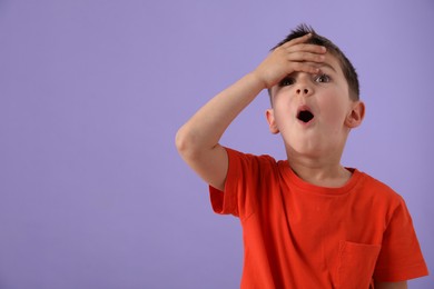 Photo of Portrait of surprised boy on purple background, space for text