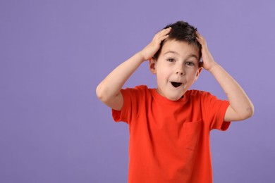 Photo of Portrait of surprised boy on purple background, space for text