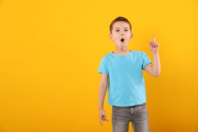 Photo of Portrait of surprised boy on orange background, space for text