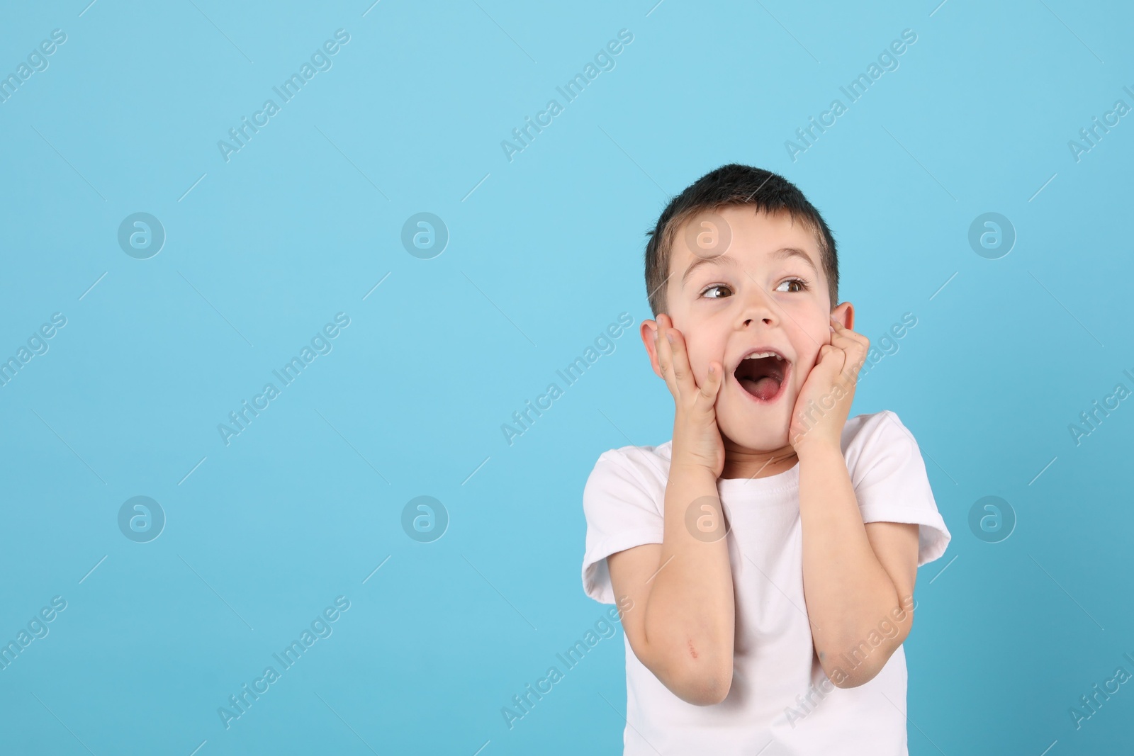 Portrait of surprised boy on light blue background, space for text Photo of Portrait of surprised boy on light blue background, space for text