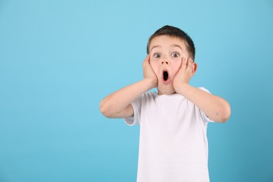 Photo of Portrait of surprised boy on light blue background, space for text