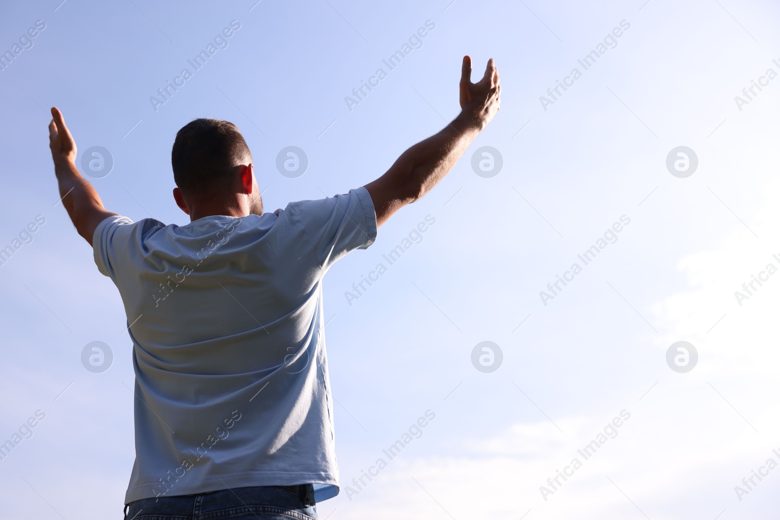 Feeling freedom. Man enjoying time outdoors against blue sky, back view. Space for text Photo of Feeling freedom. Man enjoying time outdoors against blue sky, back view. Space for text
