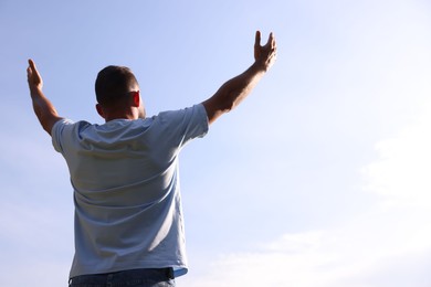 Photo of Feeling freedom. Man enjoying time outdoors against blue sky, back view. Space for text