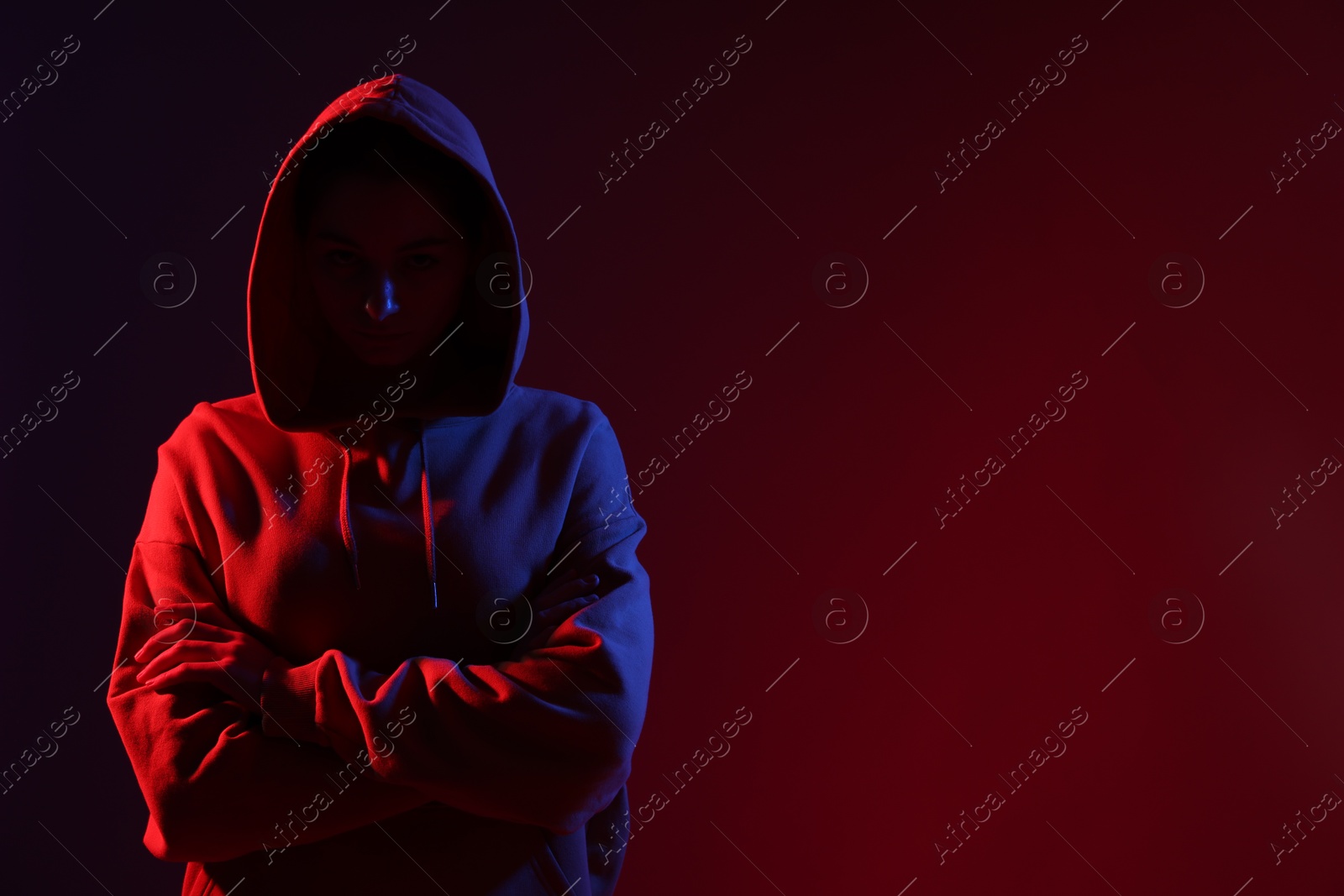 Anonymity. Woman hiding her face on dark red background, space for text Photo of Anonymity. Woman hiding her face on dark red background, space for text