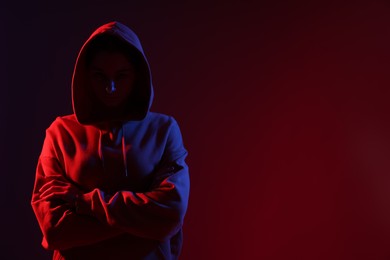 Photo of Anonymity. Woman hiding her face on dark red background, space for text