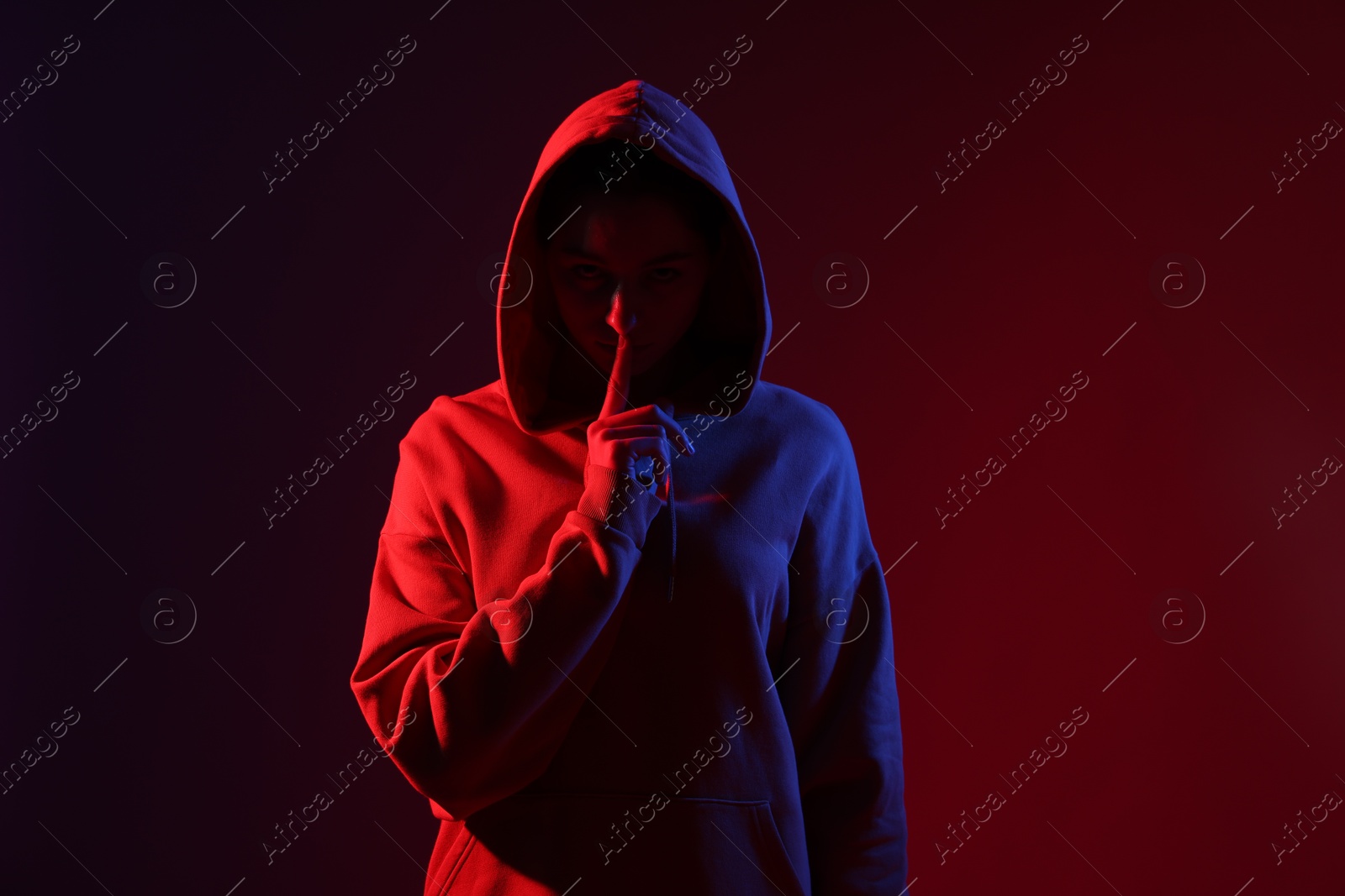 Anonymity. Woman hiding her face on dark red background Photo of Anonymity. Woman hiding her face on dark red background