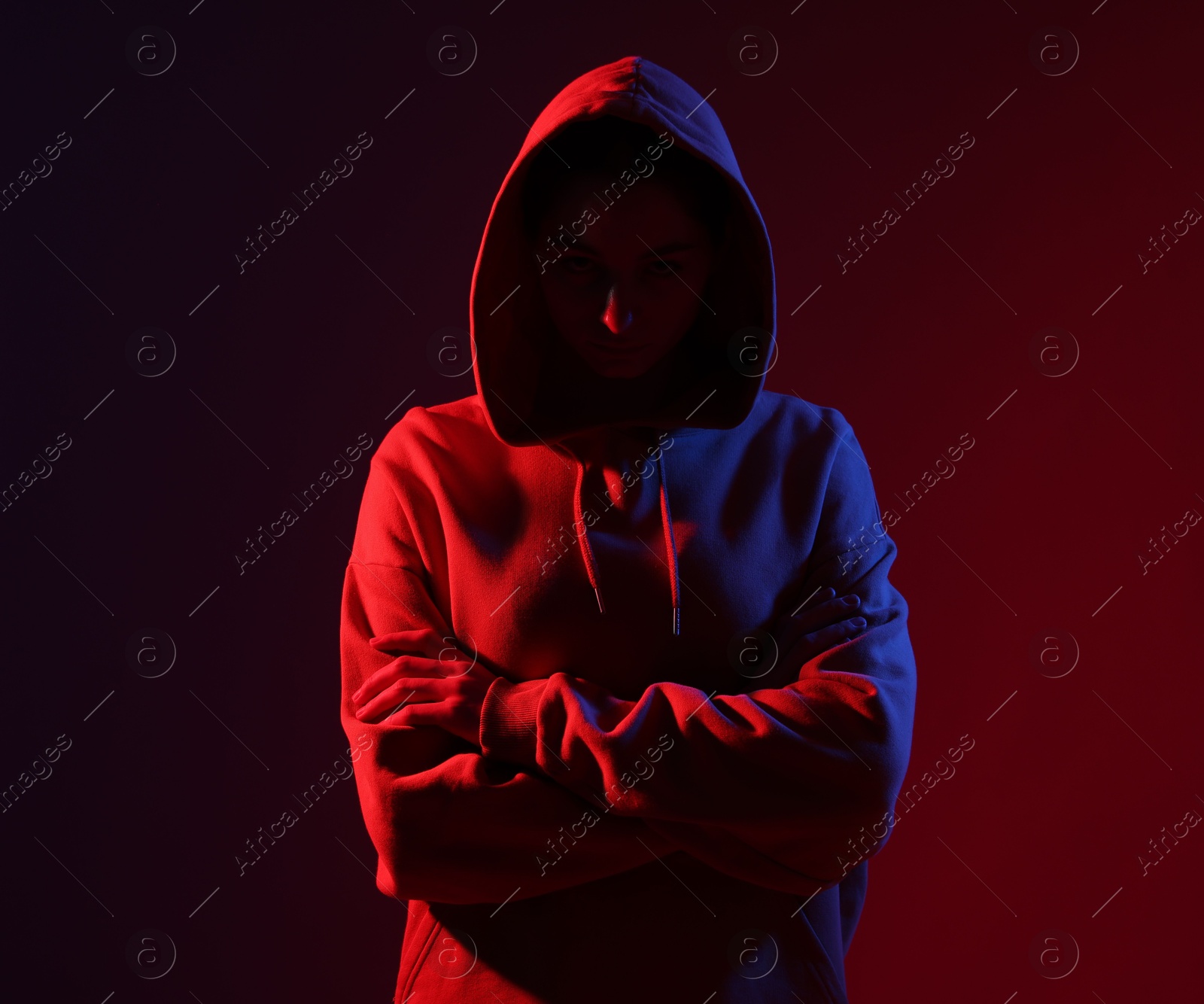 Anonymity. Woman hiding her face on dark red background Photo of Anonymity. Woman hiding her face on dark red background