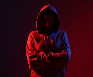Photo of Anonymity. Woman hiding her face on dark red background