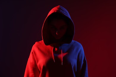 Photo of Anonymity. Woman hiding her face on dark red background