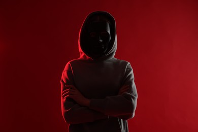 Photo of Anonymity. Woman wearing mask on red background