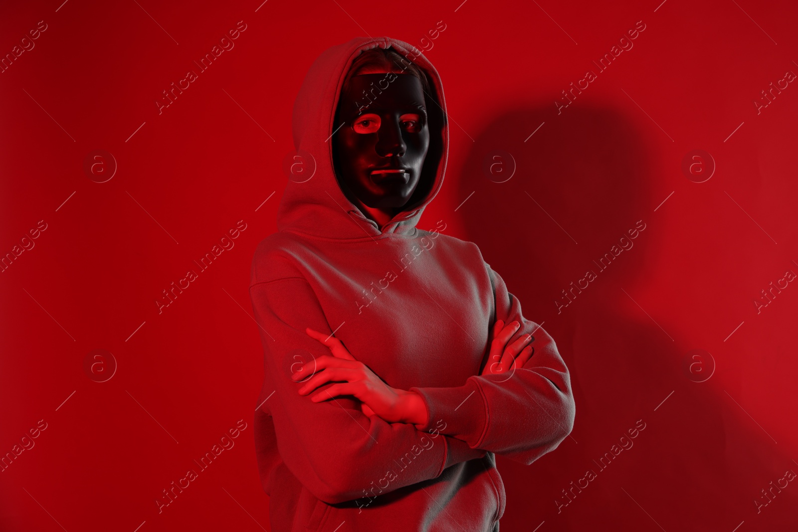 Anonymity. Woman wearing mask on red background Photo of Anonymity. Woman wearing mask on red background