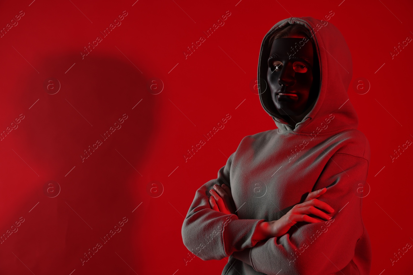 Anonymity. Woman wearing mask on red background, space for text Photo of Anonymity. Woman wearing mask on red background, space for text