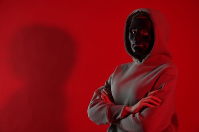 Photo of Anonymity. Woman wearing mask on red background, space for text