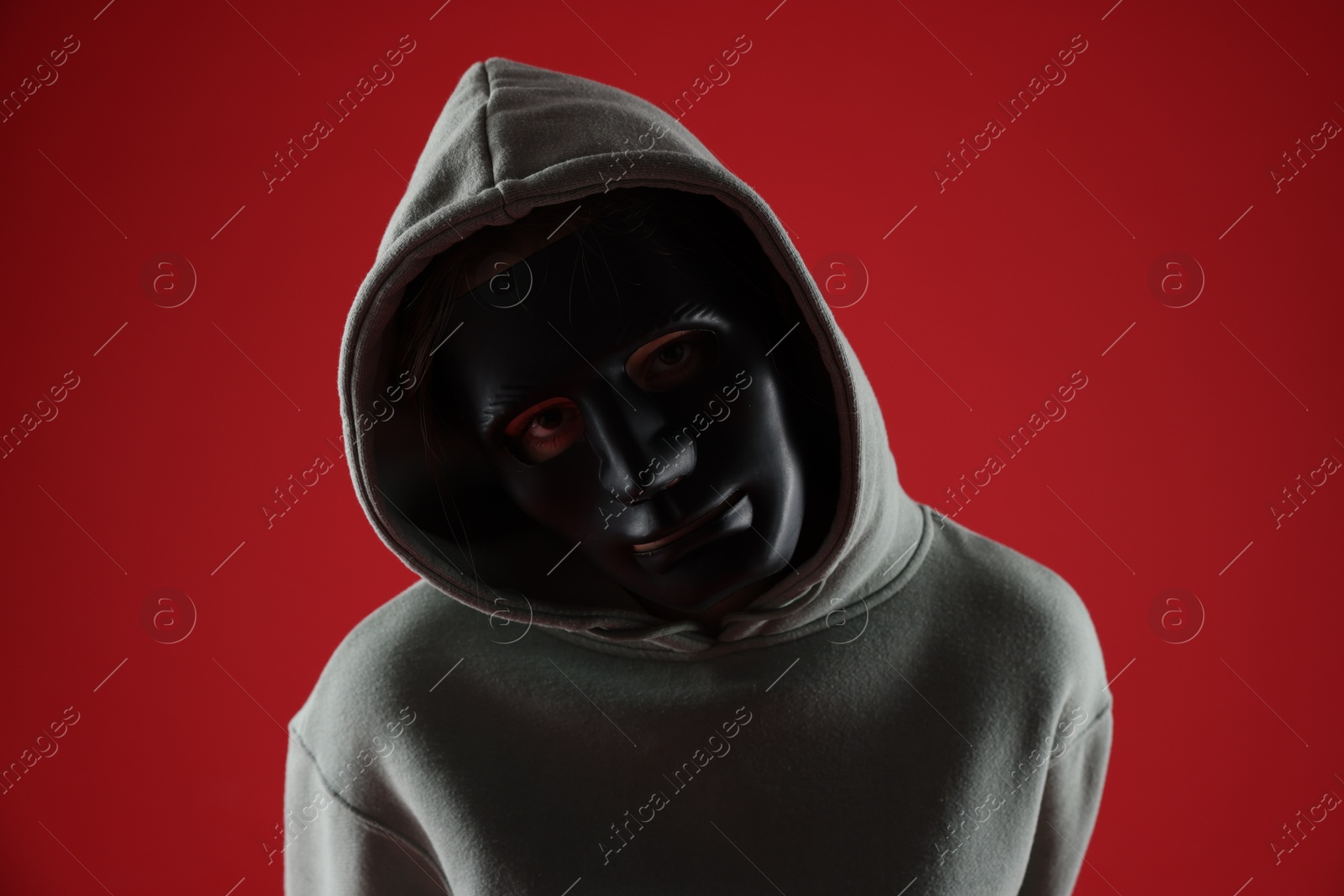 Anonymity. Woman wearing mask on red background Photo of Anonymity. Woman wearing mask on red background