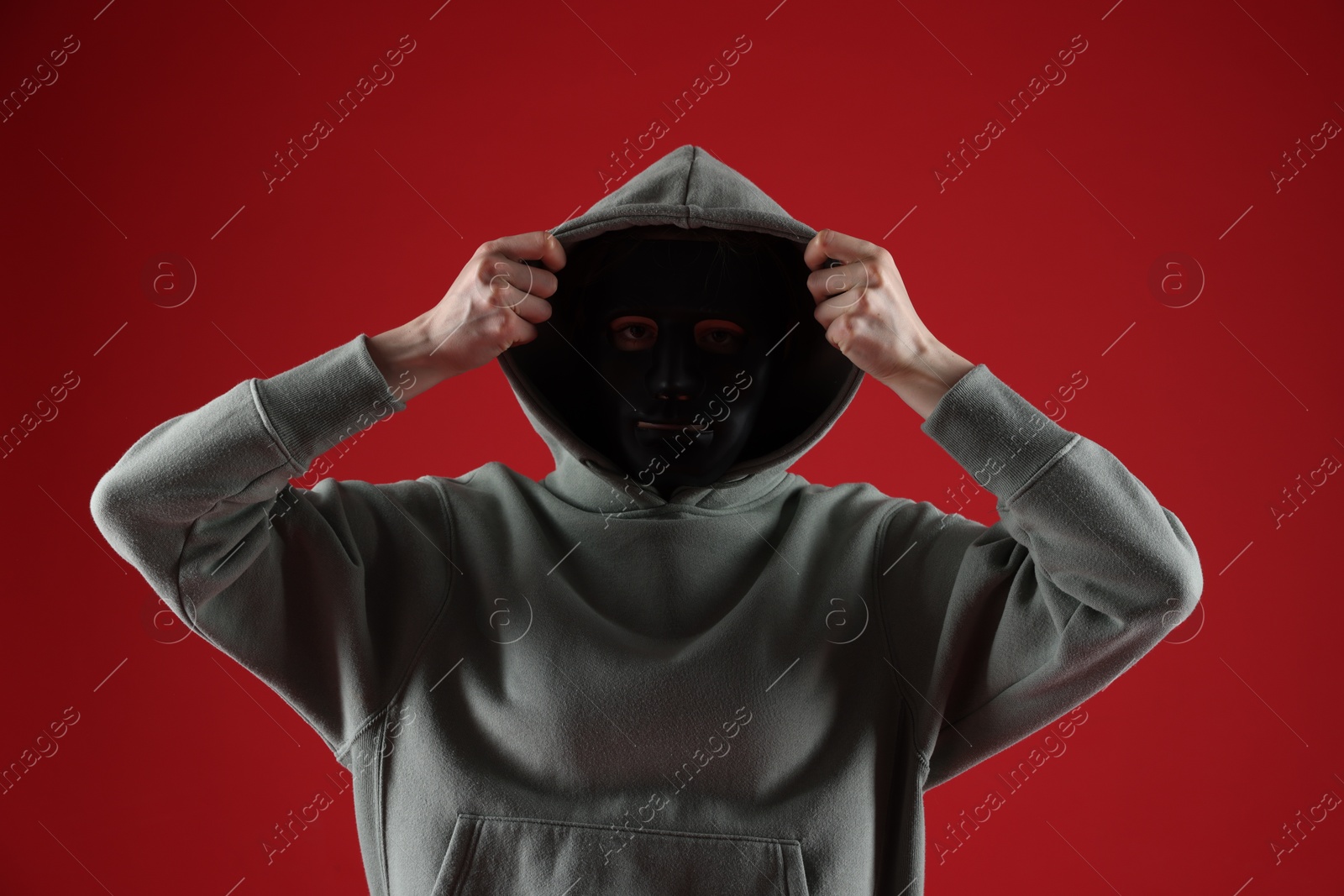 Anonymity. Woman wearing mask on red background Photo of Anonymity. Woman wearing mask on red background