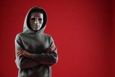 Photo of Anonymity. Woman wearing mask on red background, space for text