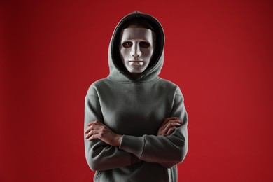 Photo of Anonymity. Woman wearing mask on red background