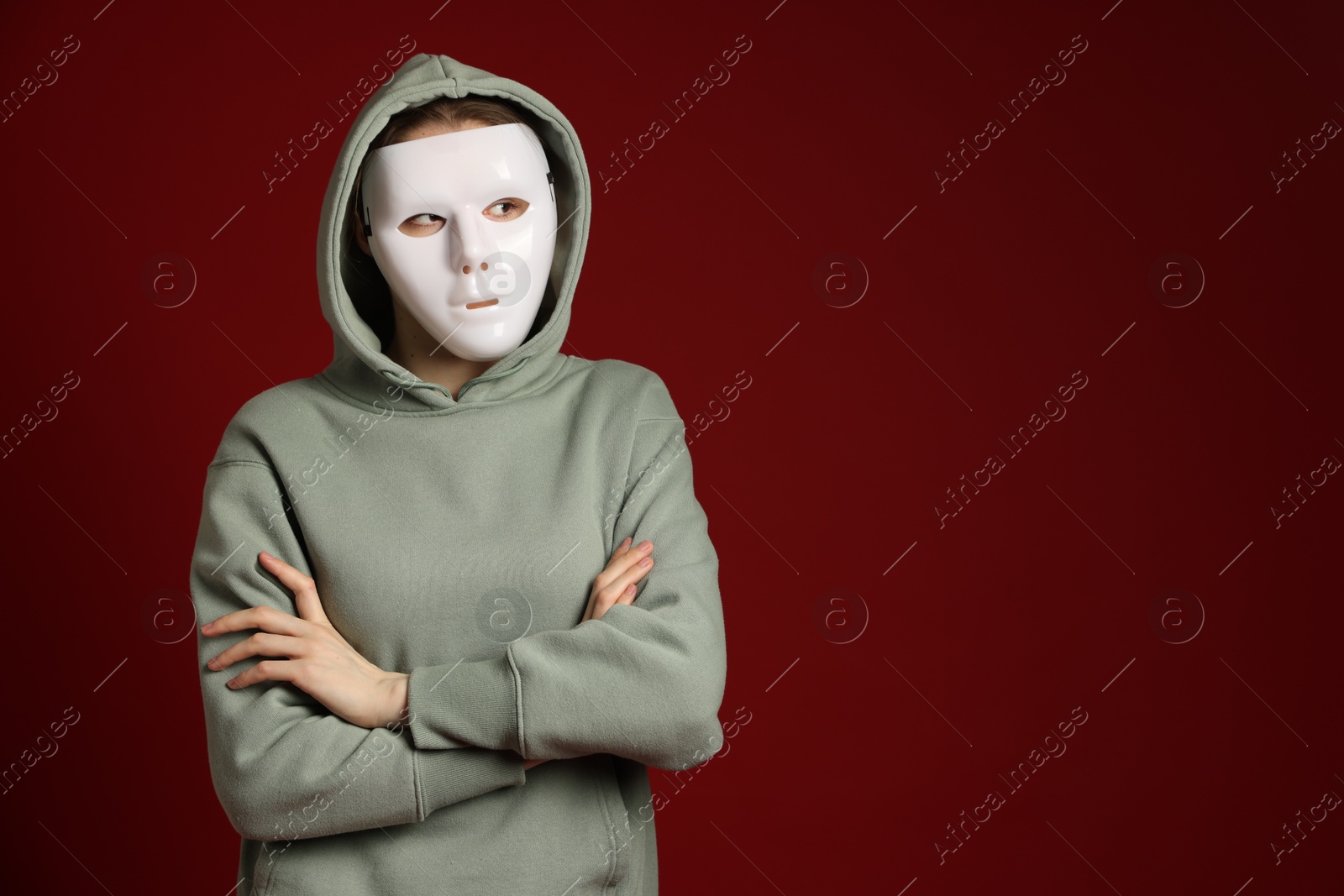 Anonymity. Woman wearing mask on dark red background, space for text Photo of Anonymity. Woman wearing mask on dark red background, space for text