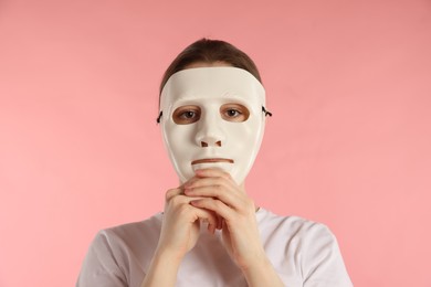Photo of Anonymity. Woman wearing mask on pink background