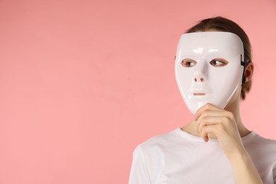 Photo of Anonymity. Woman wearing mask on pink background, space for text