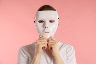 Photo of Anonymity. Woman wearing mask on pink background