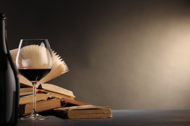 Photo of Red wine and books on dark textured table. Space for text
