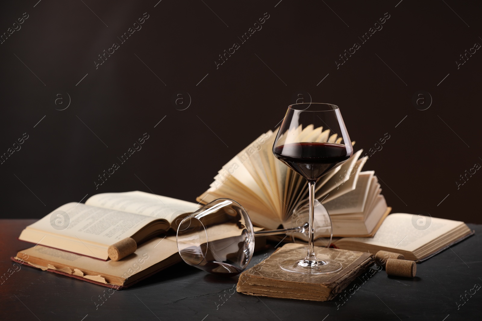 Red wine and books on grey textured table against dark background Photo of Red wine and books on grey textured table against dark background