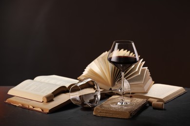 Photo of Red wine and books on grey textured table against dark background