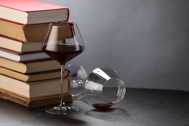 Photo of Red wine and stack of books on grey textured table, closeup. Space for text