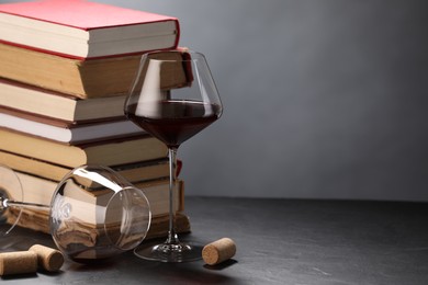 Photo of Red wine and stack of books on grey textured table, closeup. Space for text