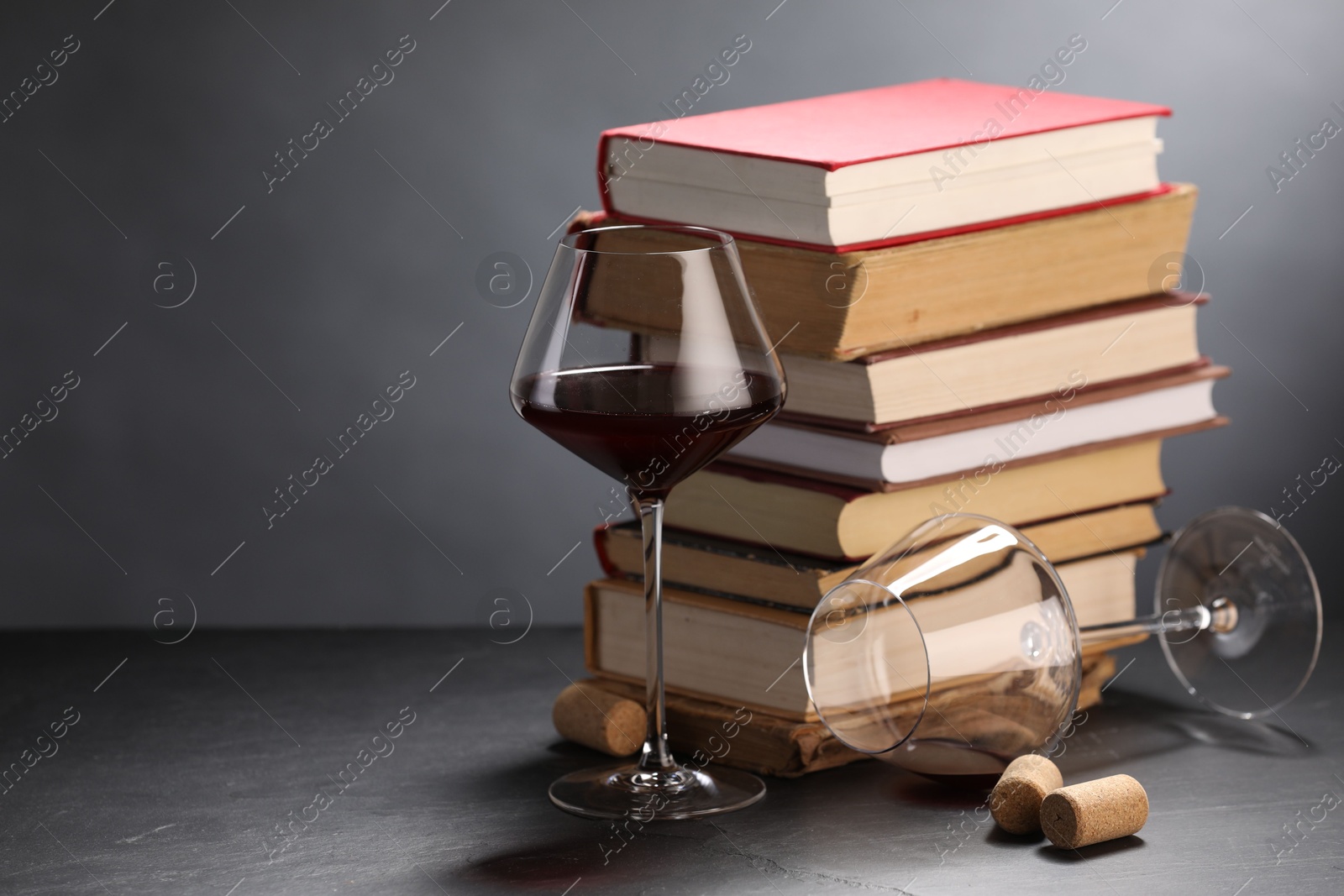 Red wine and stack of books on grey textured table, closeup. Space for text Photo of Red wine and stack of books on grey textured table, closeup. Space for text