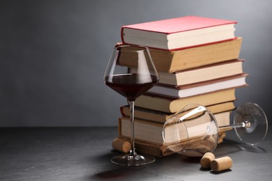 Photo of Red wine and stack of books on grey textured table, closeup. Space for text