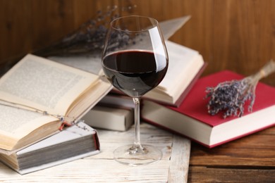 Photo of Red wine in glass and books on wooden table, closeup