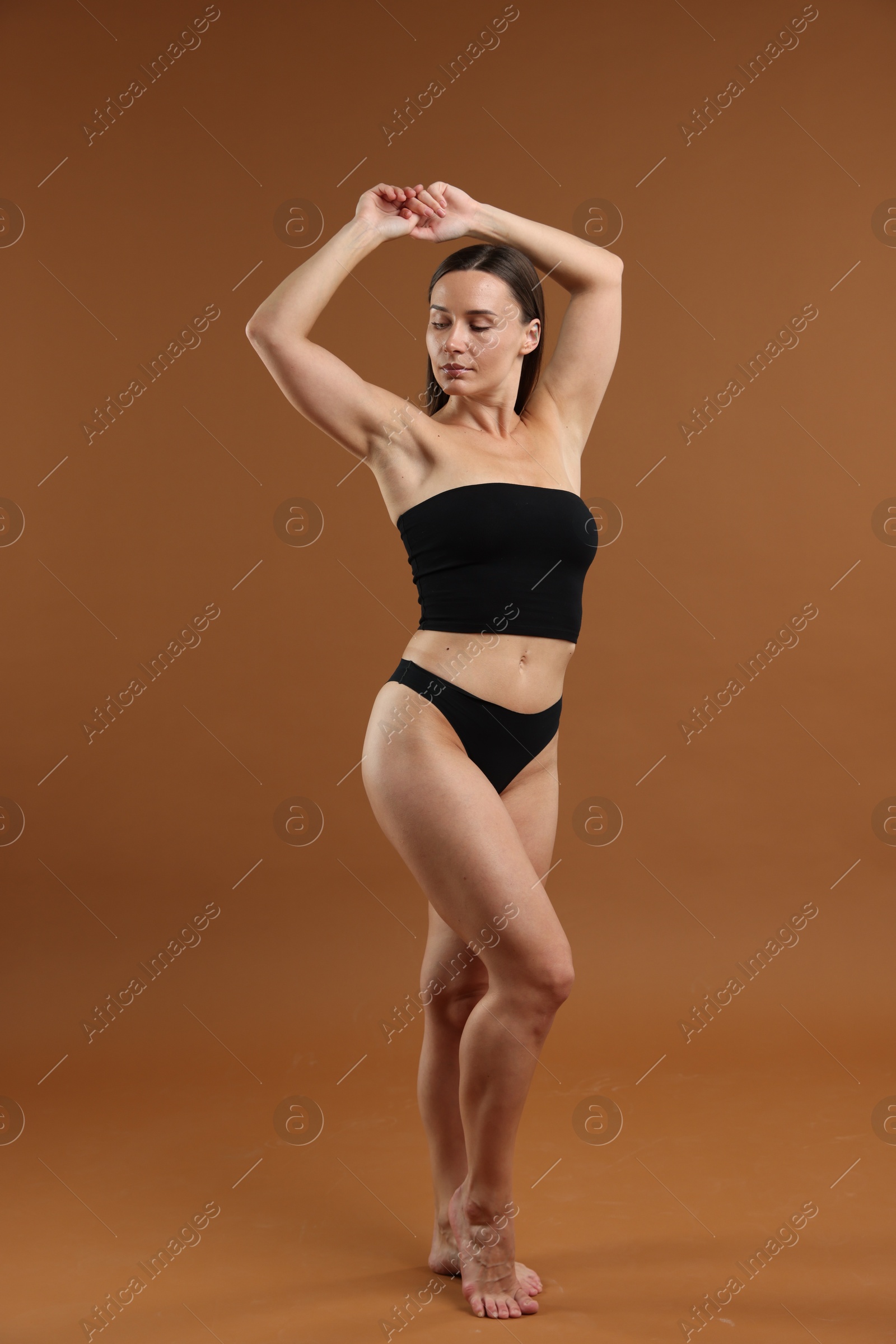 Fit woman with perfect body on brown background Photo of Fit woman with perfect body on brown background