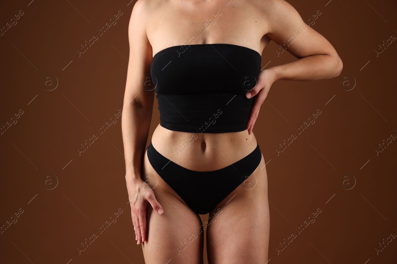 Fit woman with perfect body on brown background, closeup Photo of Fit woman with perfect body on brown background, closeup