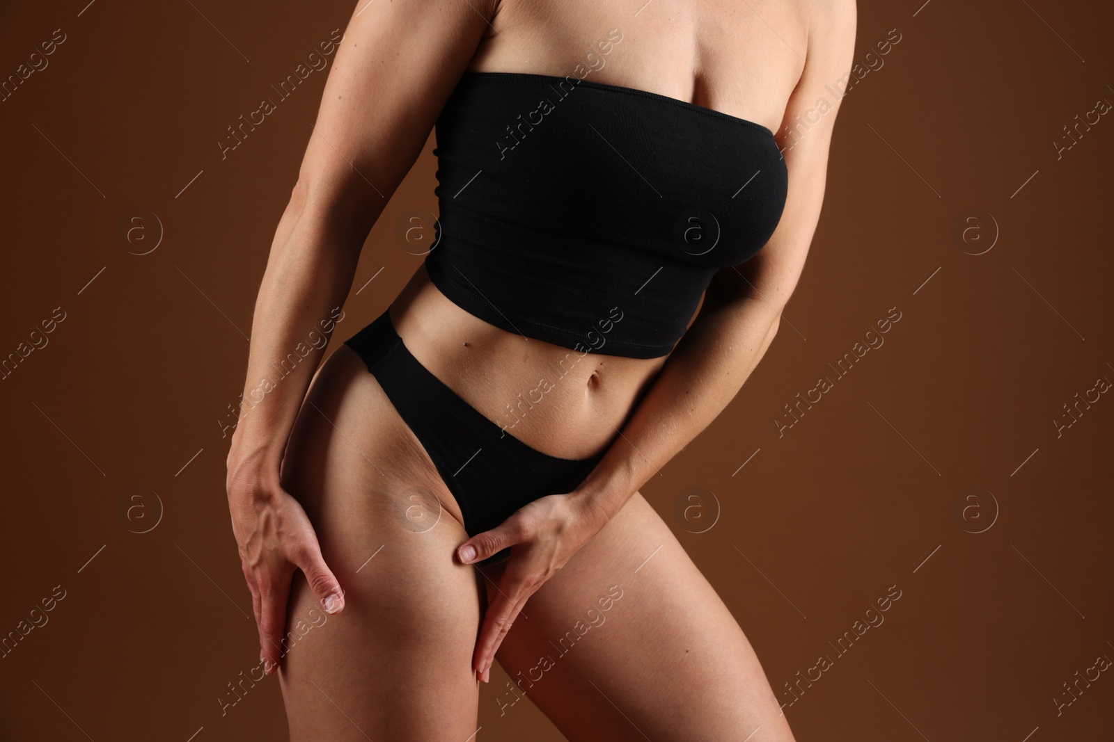 Fit woman with perfect body on brown background, closeup Photo of Fit woman with perfect body on brown background, closeup