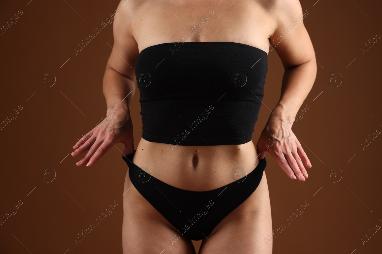 Fit woman with perfect body on brown background, closeup Photo of Fit woman with perfect body on brown background, closeup