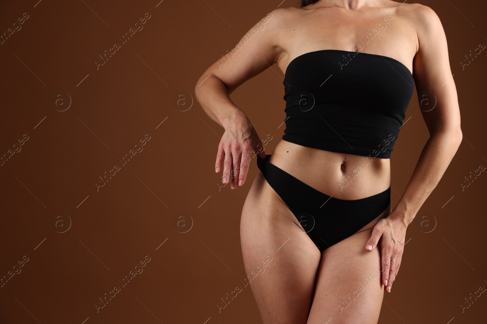 Fit woman with perfect body on brown background, closeup. Space for text Photo of Fit woman with perfect body on brown background, closeup. Space for text