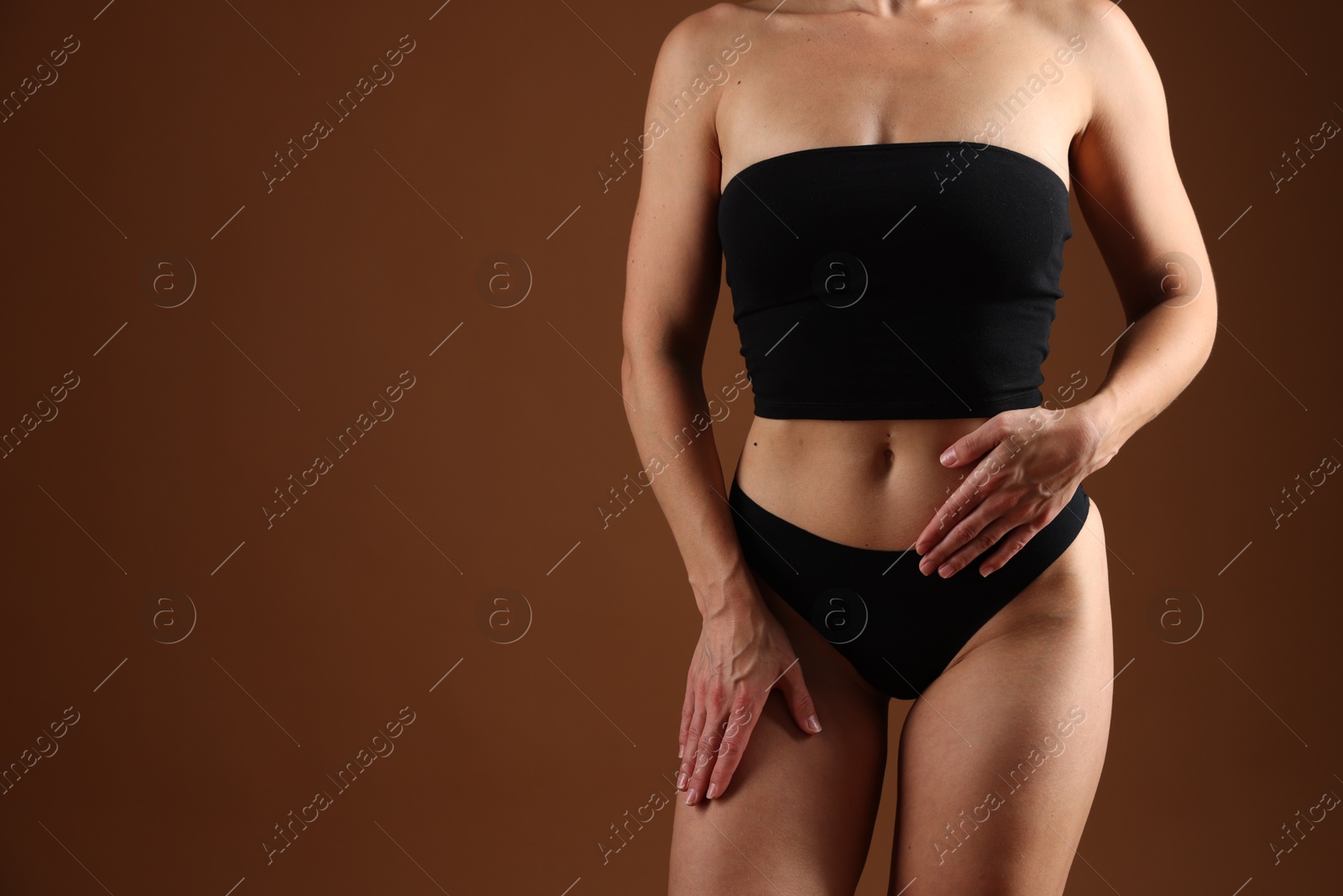 Fit woman with perfect body on brown background, closeup. Space for text Photo of Fit woman with perfect body on brown background, closeup. Space for text