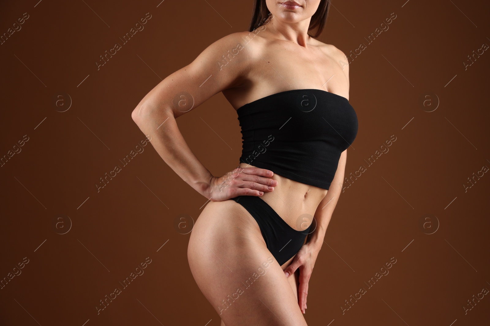 Fit woman with perfect body on brown background, closeup Photo of Fit woman with perfect body on brown background, closeup